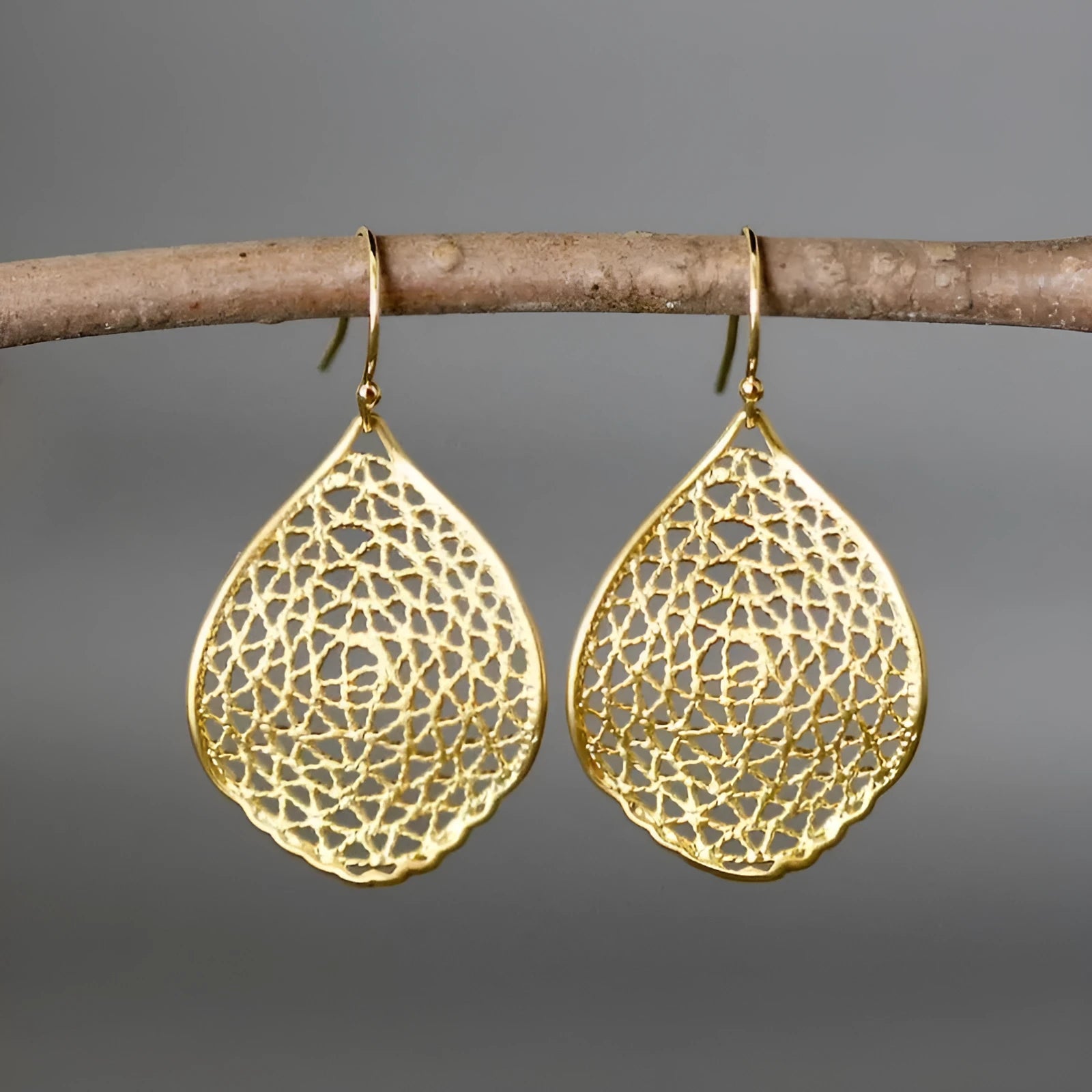 Gold drop-shaped pendant earrings with hollow leaf design and retro styling details