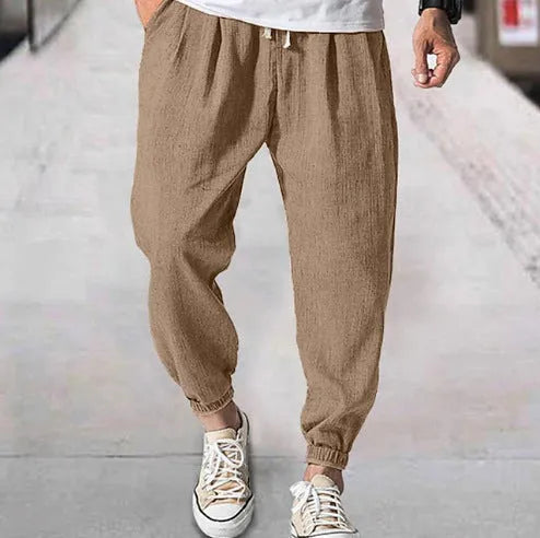 Men's loose-fit light green cotton casual trousers with a banded ankle cuff on a plain background.