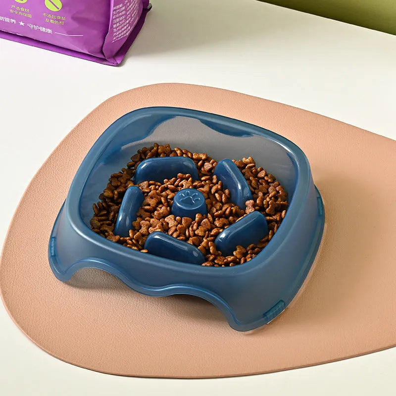 Blue plastic slow-feed dog bowl on a floor to prevent choking.
