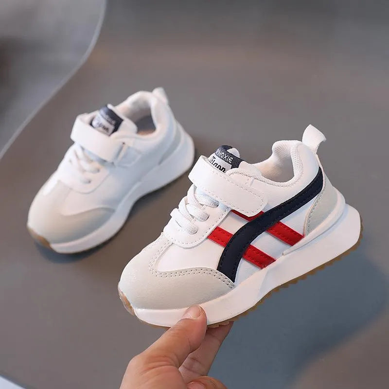 Children's solid-colour sneakers with Velcro strap closure and rubber sole.