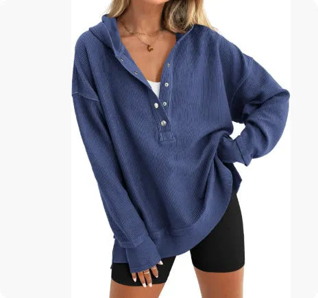 A woman wearing a loose peacock green pullover sweater with raglan sleeves.