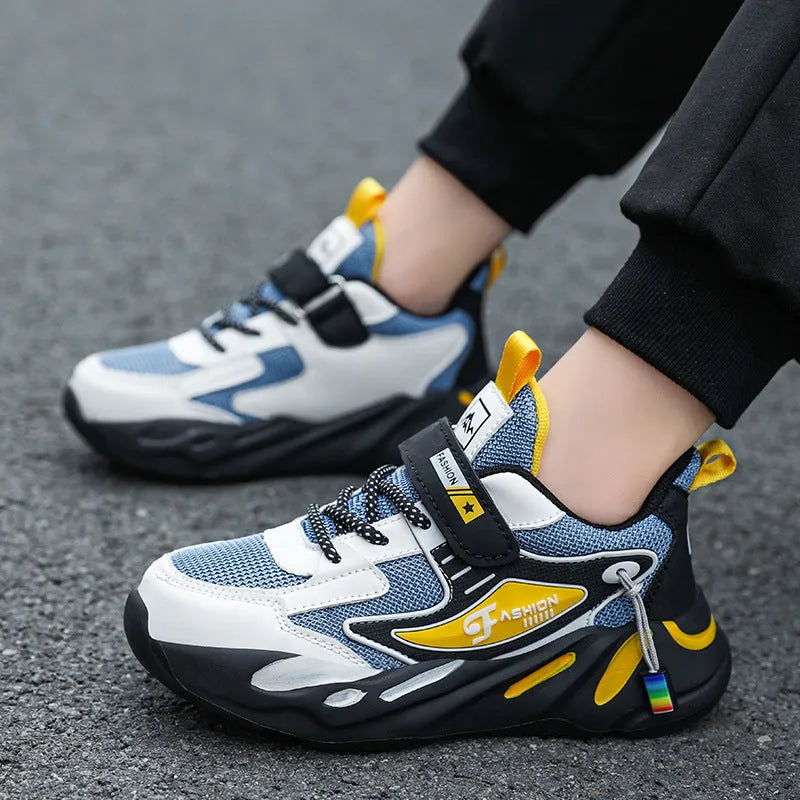 Boy's blue sports running shoe with velcro strap and mesh upper on a hard ground surface.