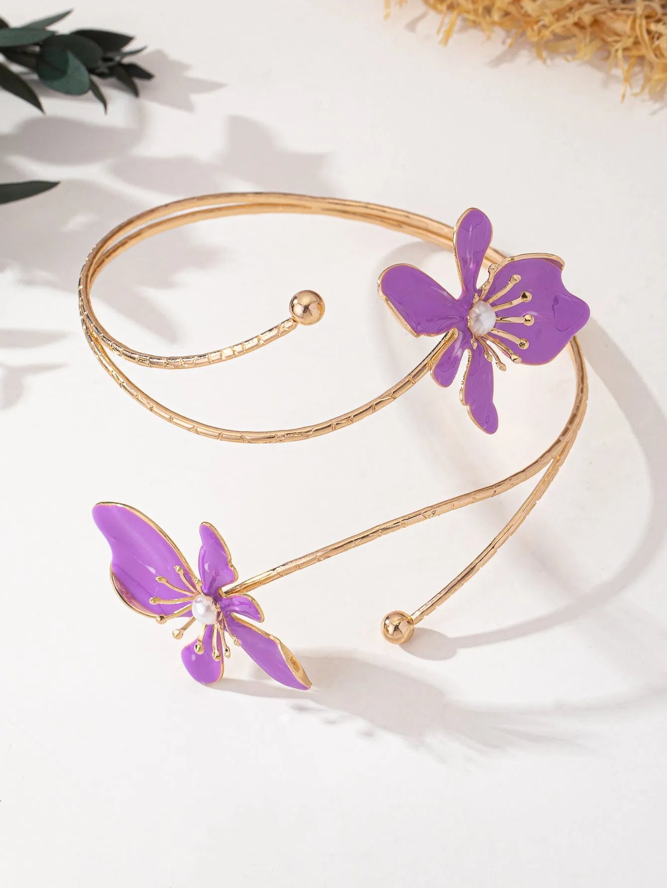 Pink hollow metal bangle with engraved pattern on a wrist, showing its open design and lightweight profile.