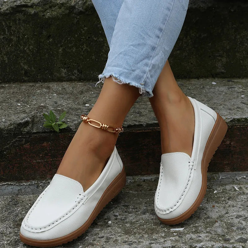 Women's black PU leather slip-on loafers with a round toe and flat rubber sole on a white background.