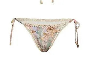 Women's creamy-white floral bikini swimsuit set with matching skirt on a beach background.