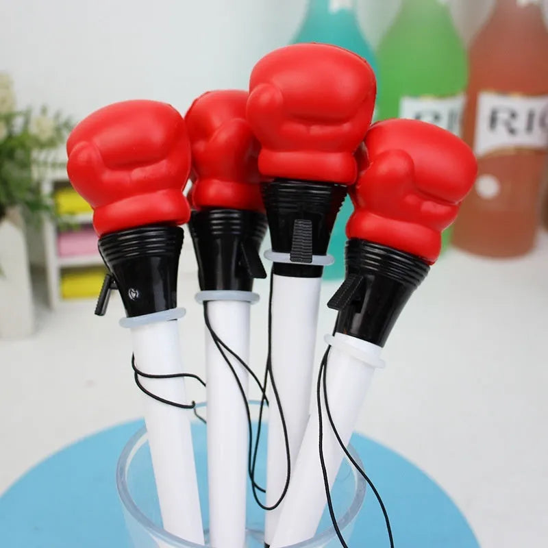 Boxing pressure pen ejection press stationery toy with four black pens on a desk.