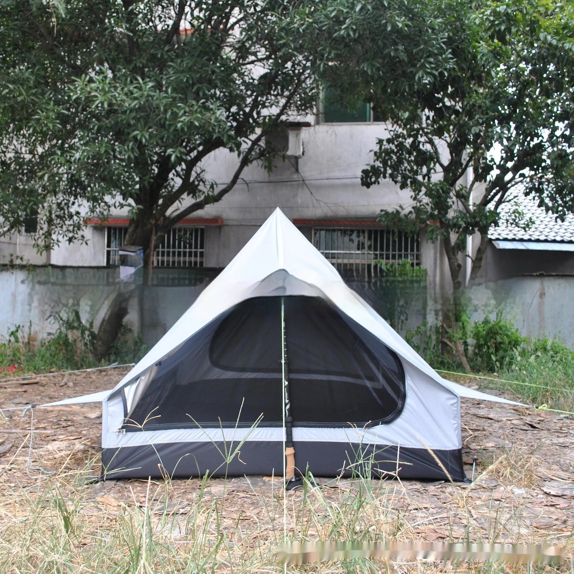 Brown and white pole-free A-line cabin tent for 2-3 people shown pitched with hiking poles.