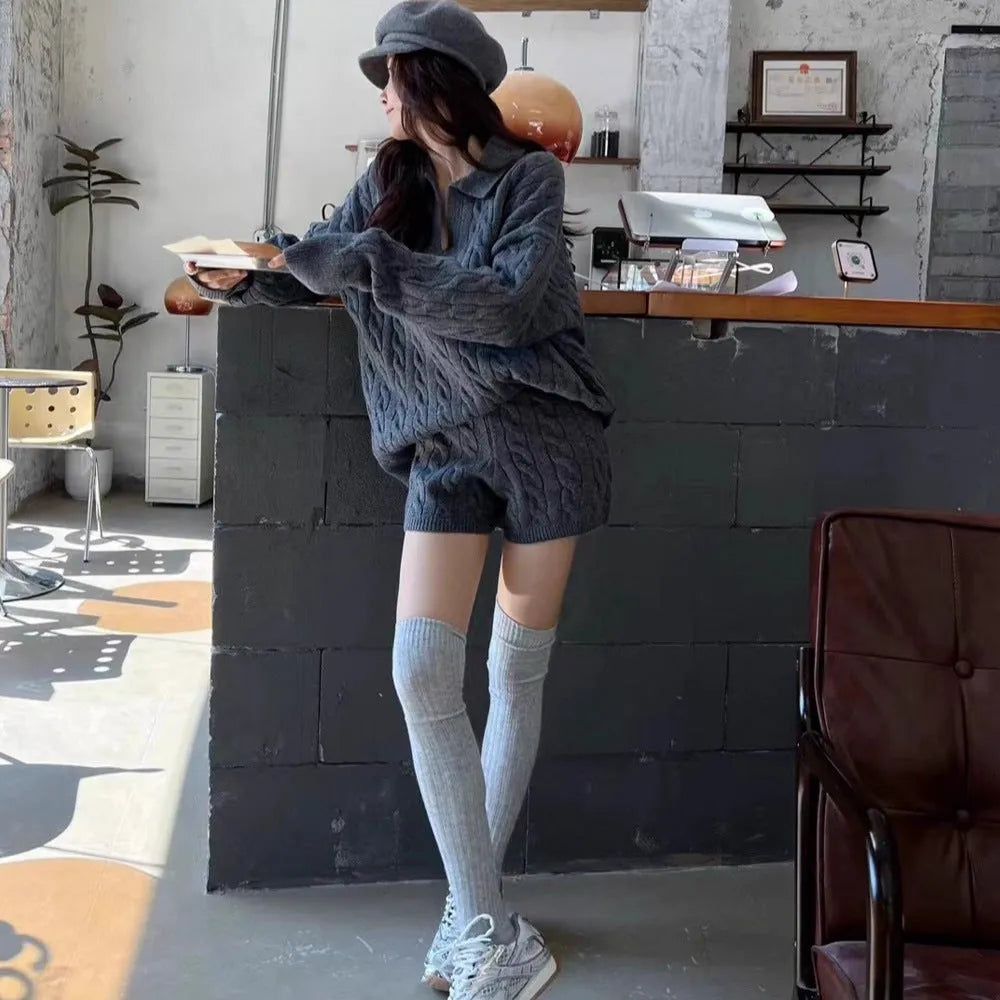 Woman wearing a creamy-white cable-knit long-sleeve sweater and matching elastic-waist knitted shorts from a two-piece set.