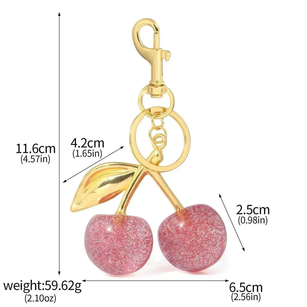 Close-up of a red zinc alloy keychain pendant with a three-dimensional cherry design.
