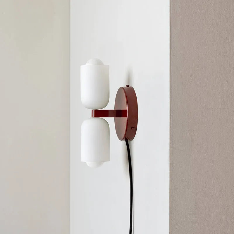 Cream base double head wall lamp with white glass shades against wall