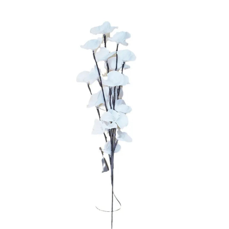 Pink fabric and plastic LED Phalaenopsis orchid branch light, 65cm long, on a table providing warm white ambient glow.