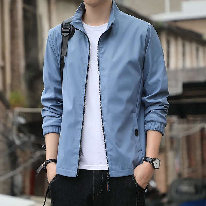 Man wearing a loose-fit black casual autumn jacket with a lapel and zippered pockets.