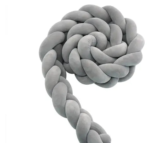 Close-up of a grey braid knot pillow cushion cot bumper fitted around white crib rails.