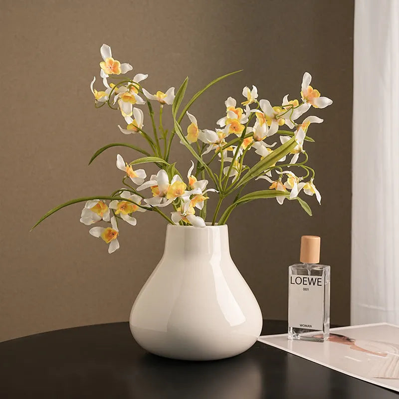 Modern ceramic vase with two white artificial orchid stems in minimalist home setting