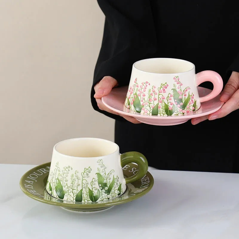 Ceramic coffee cup and saucer set for two with stirring spoons in couple's cup design.