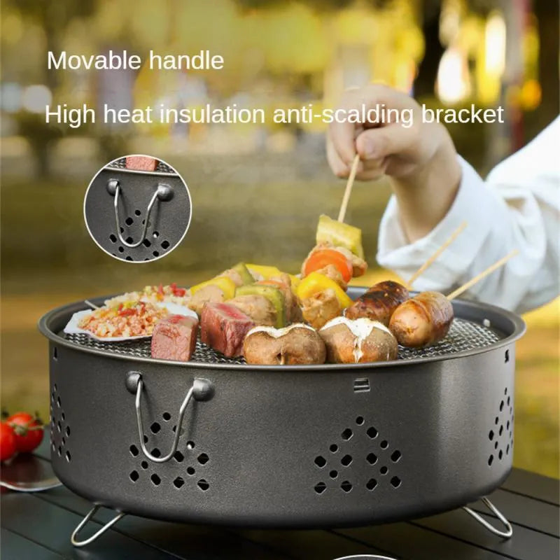 Portable stainless steel barbecue grill with detachable parts on a grassy outdoor surface.