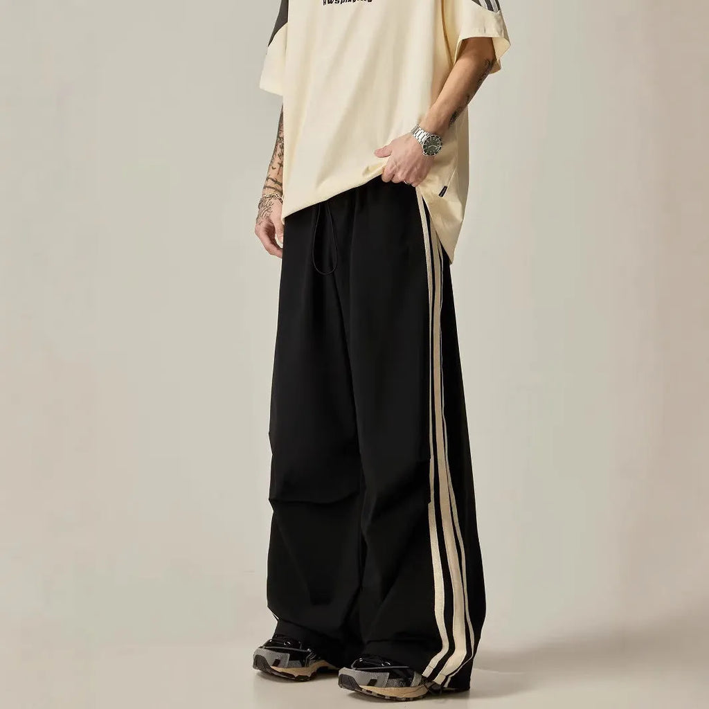 Black wide-leg straight-cut men's climbing trousers with a high waist on a hanger.