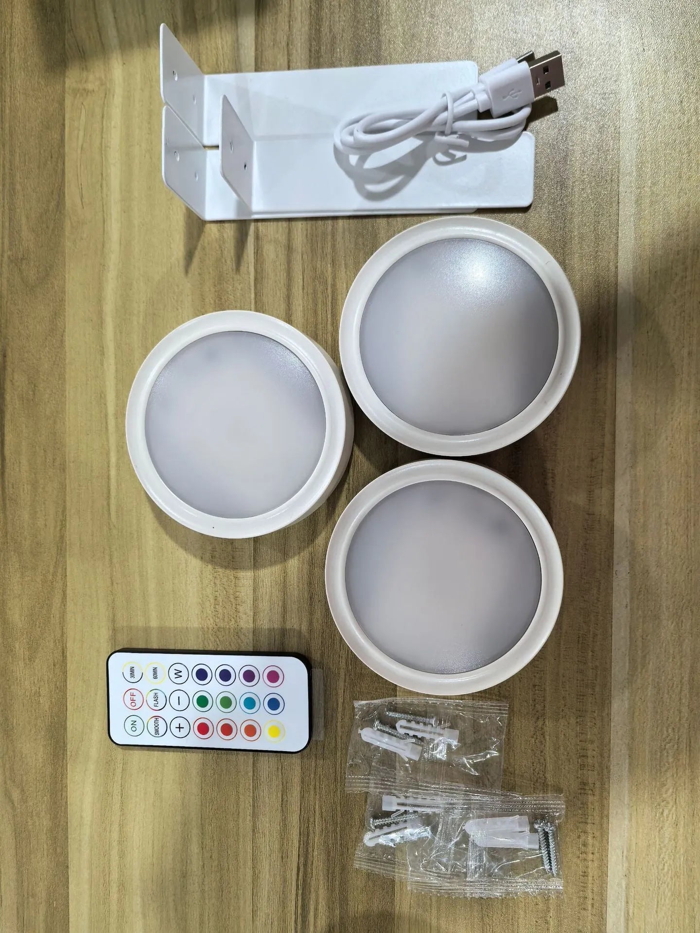 Black magnetic wireless LED lamp with remote control mounted next to a painting on a wall.
