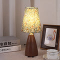 Nordic retro style ceramic table lamp with a tapered floral pleated shade and remote control on a wooden surface.