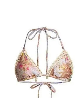 Women's creamy-white floral bikini swimsuit set with matching skirt on a beach background.