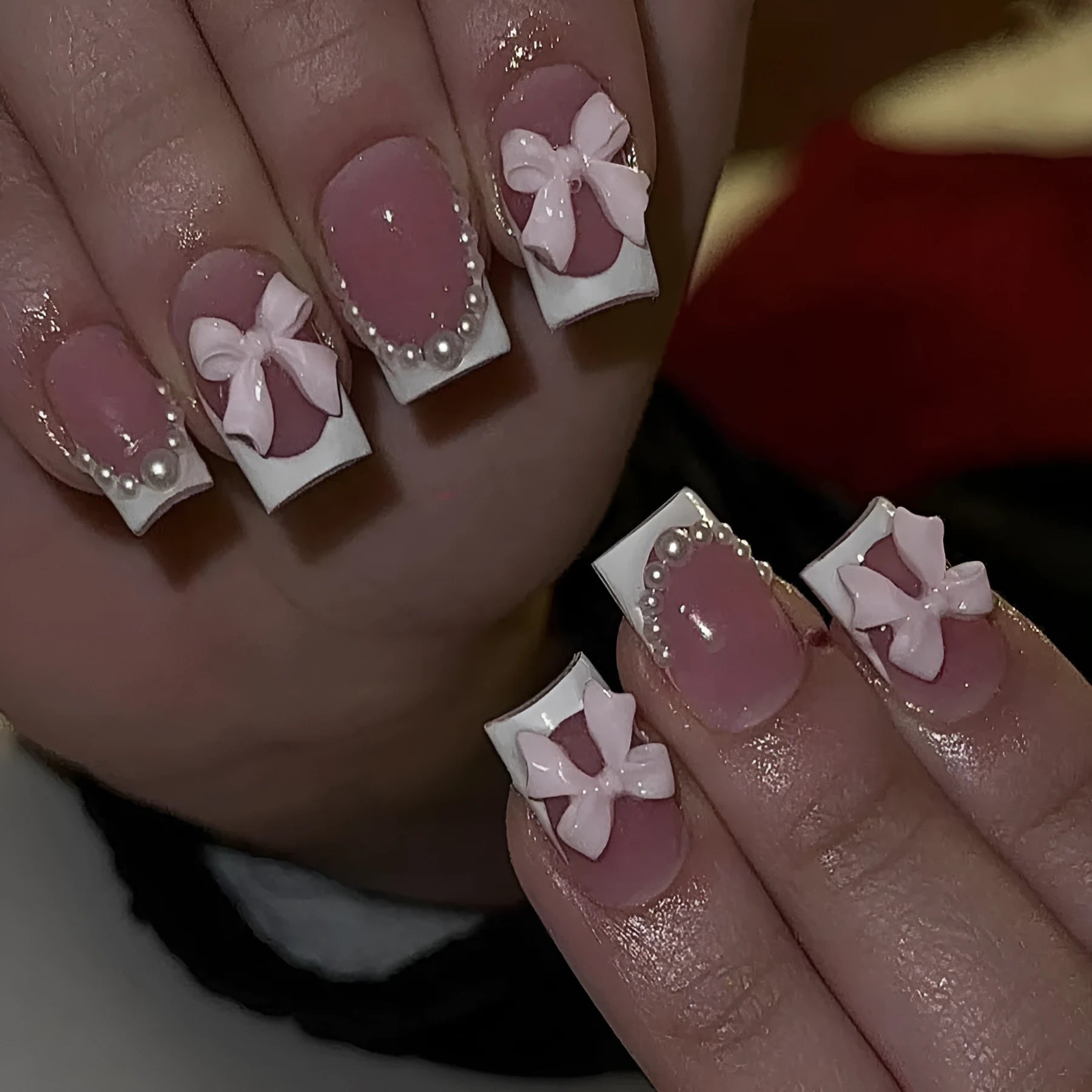Short white French tip press-on nails with a cute pink bow design and a tulip pattern on a blush base.