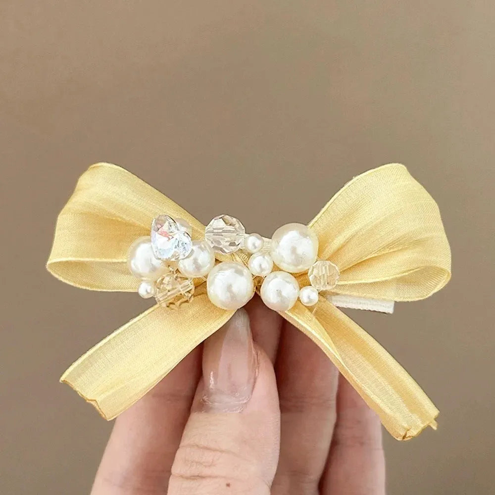 Yellow cloth bow hair clip with rhinestone pearls on duckbill clip mechanism