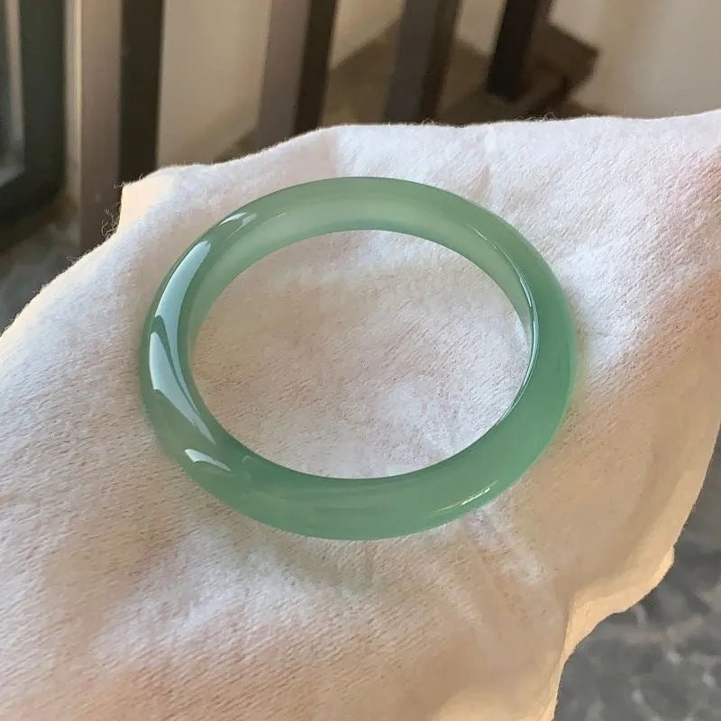 Natural agate wide tire bracelet in pink on a wrist, showing polished bead design.