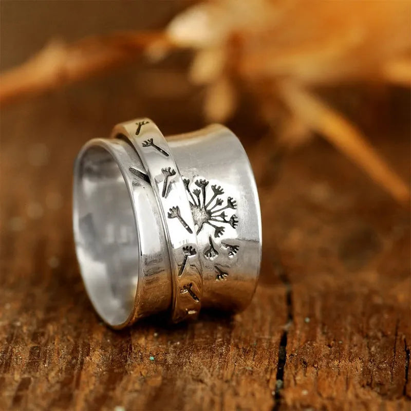 Silver rotating flower ring with movable petals on a finger, showing the kinetic jewellery design