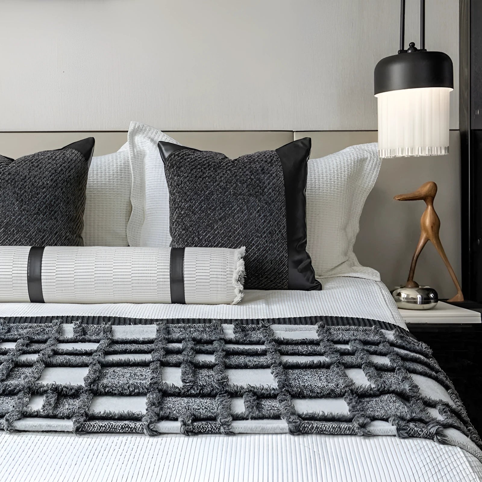 Modern grey and white plaid bed runner blanket with matching pillowcase and round pillow on a bed.