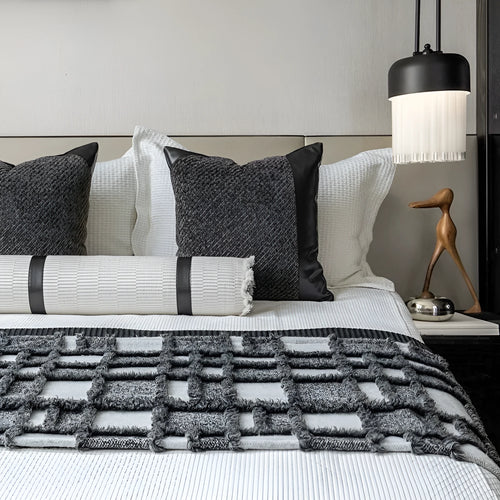 Grey and white plaid bed runner blanket set with a leather round pillow on a modern bed.