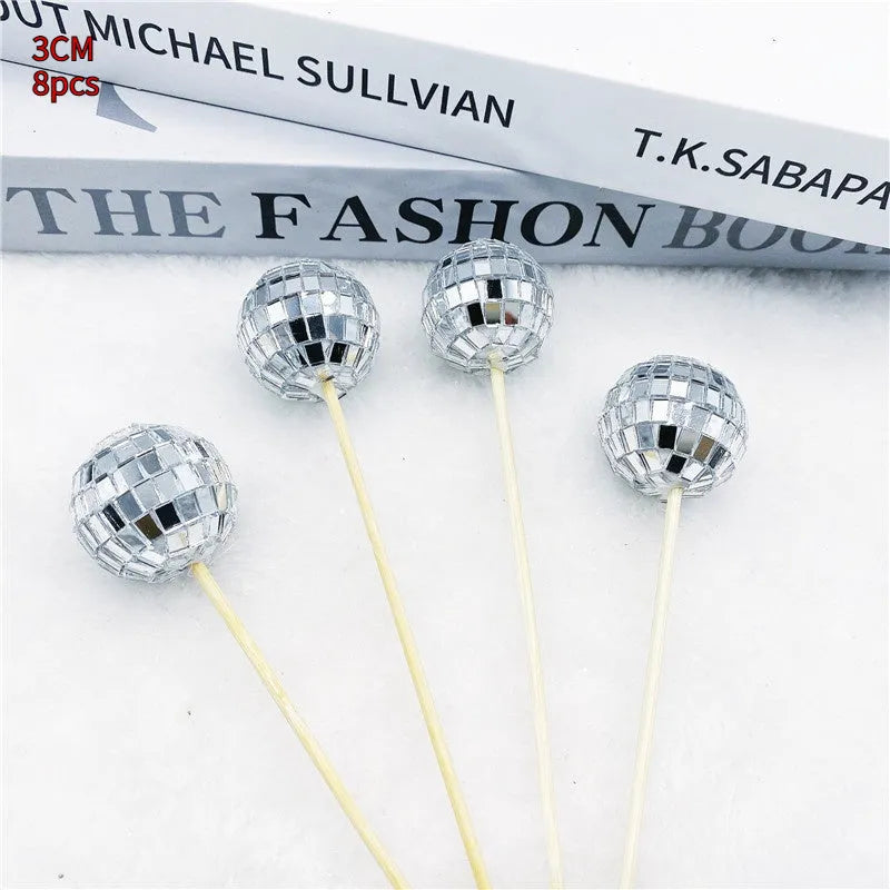 Small glass mirrored disco ball cake decoration attached to a thin wooden stick.