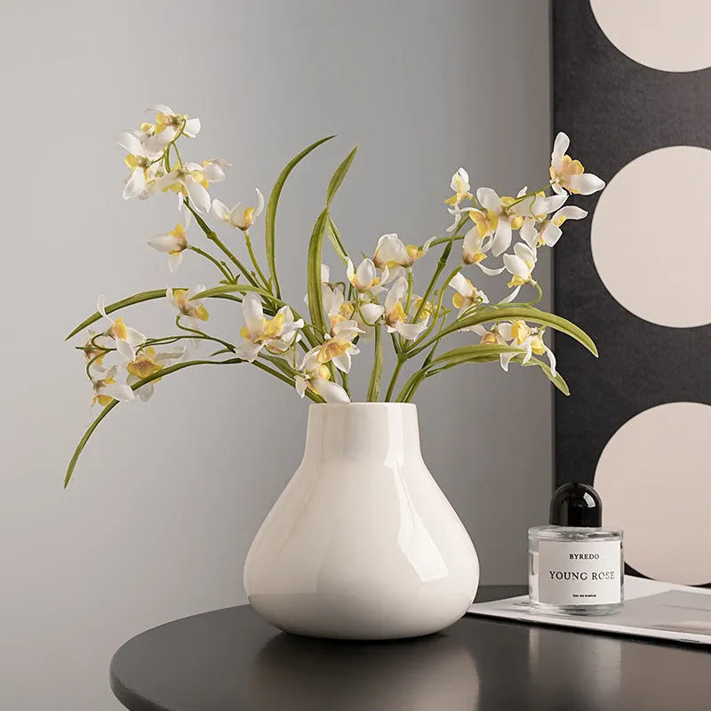 Modern ceramic vase with two white artificial orchid stems in minimalist home setting