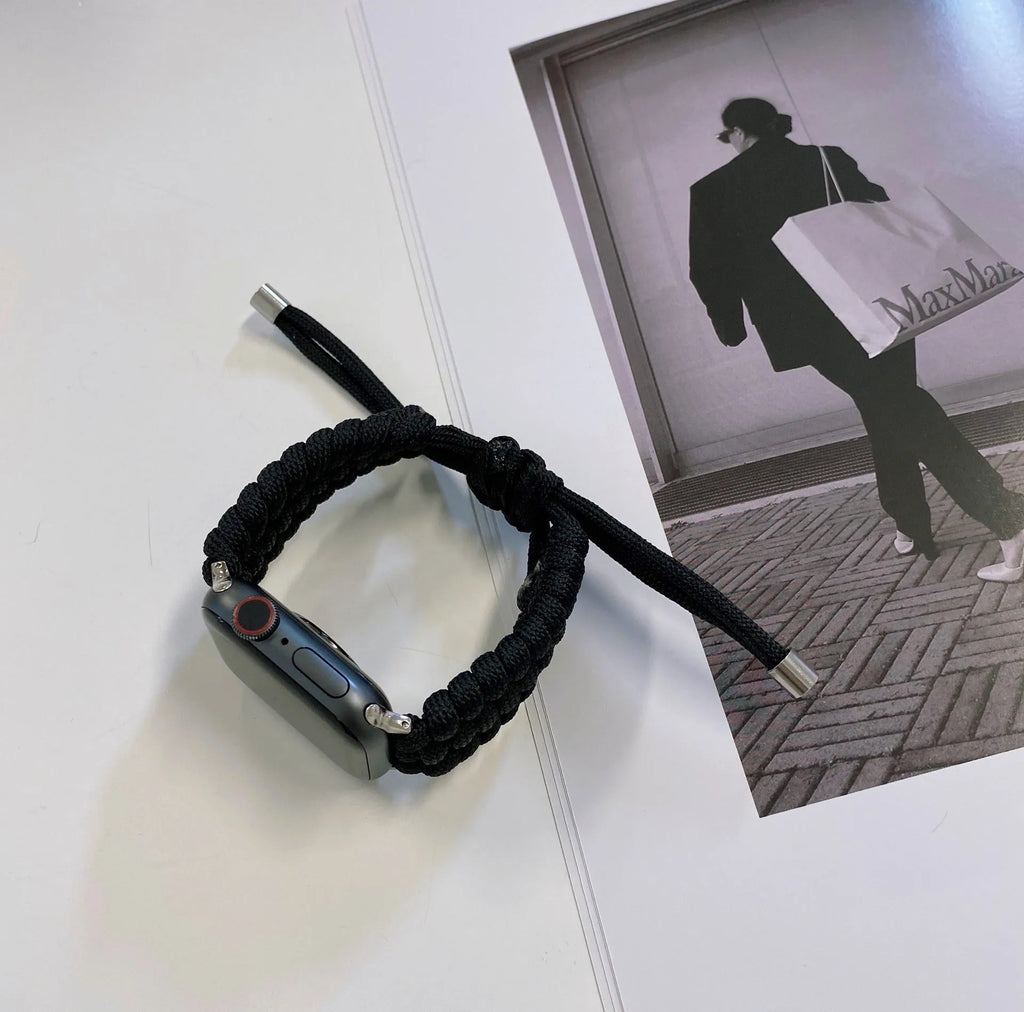 Paracord braided smartwatch strap in black on a watch, showing textured weave and connector lugs.