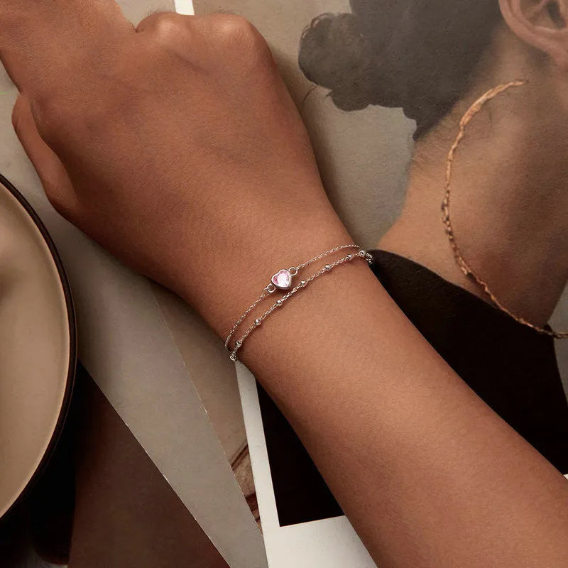 Women's sterling silver bracelet with a small heart-shaped pendant on an adjustable chain.