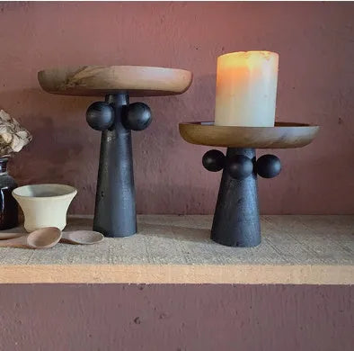 Round high-legged wooden tray in modern style holding a candle and perfume bottle for home decor.
