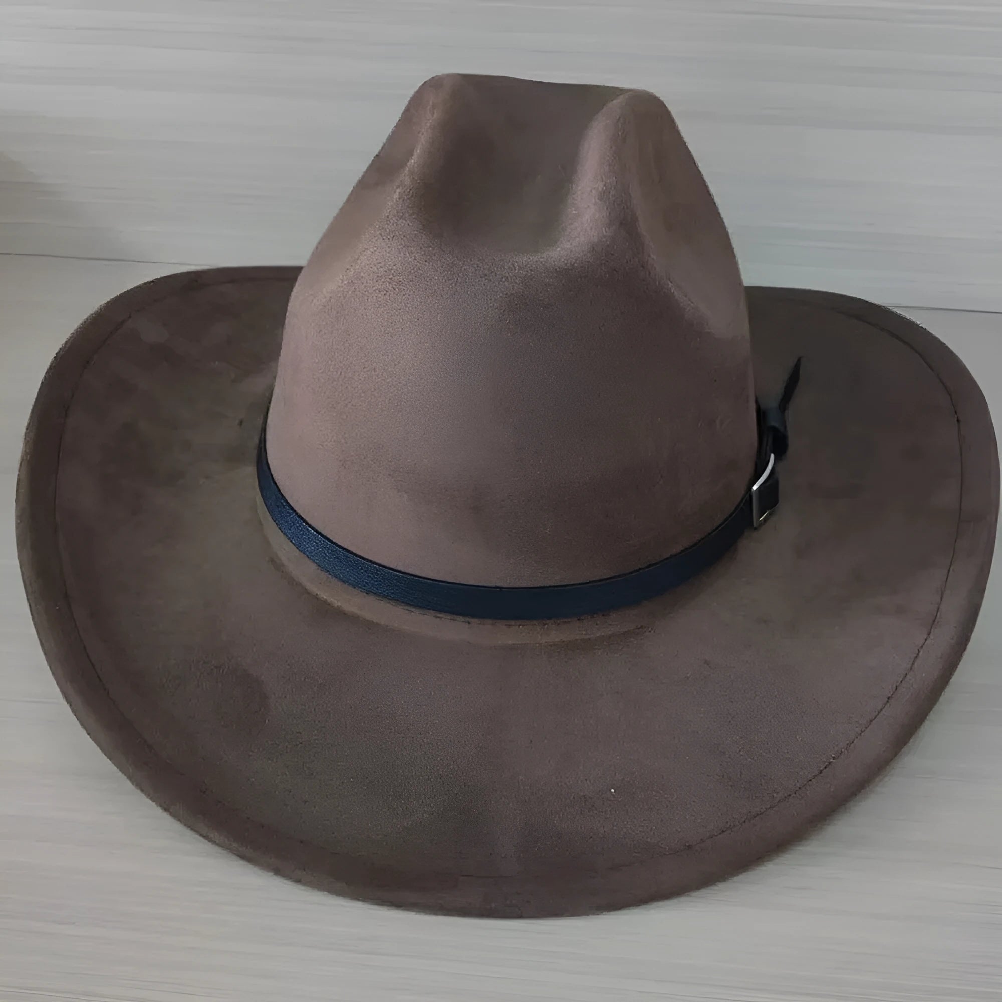 Brown leather velvet cowboy hat with curved brim and conical crown on a wooden post.