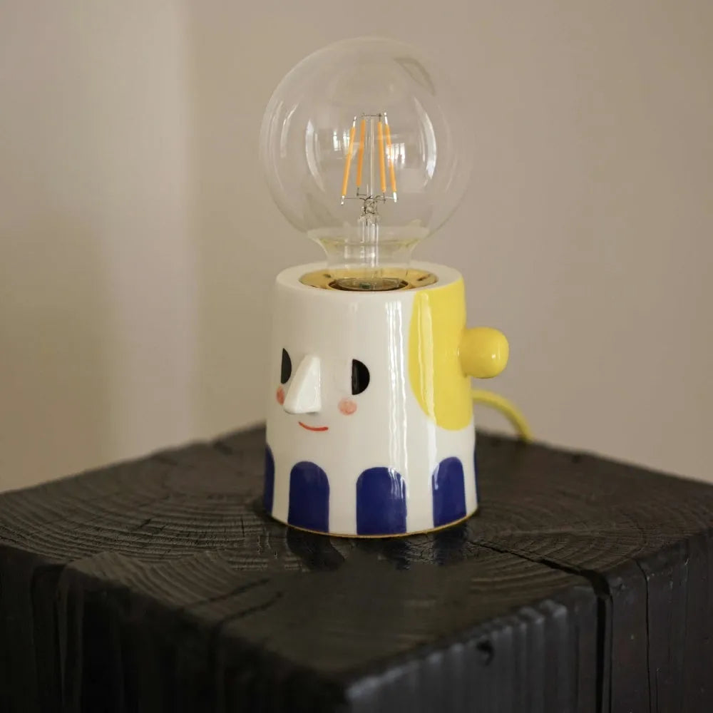 Handmade white ceramic table lamp with a spherical ball-shaped shade on a wooden surface.