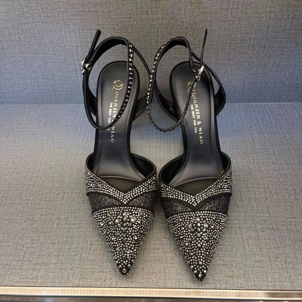 Women's silver and black hollow stiletto high heels with pointed toe and red sole on a plain background.