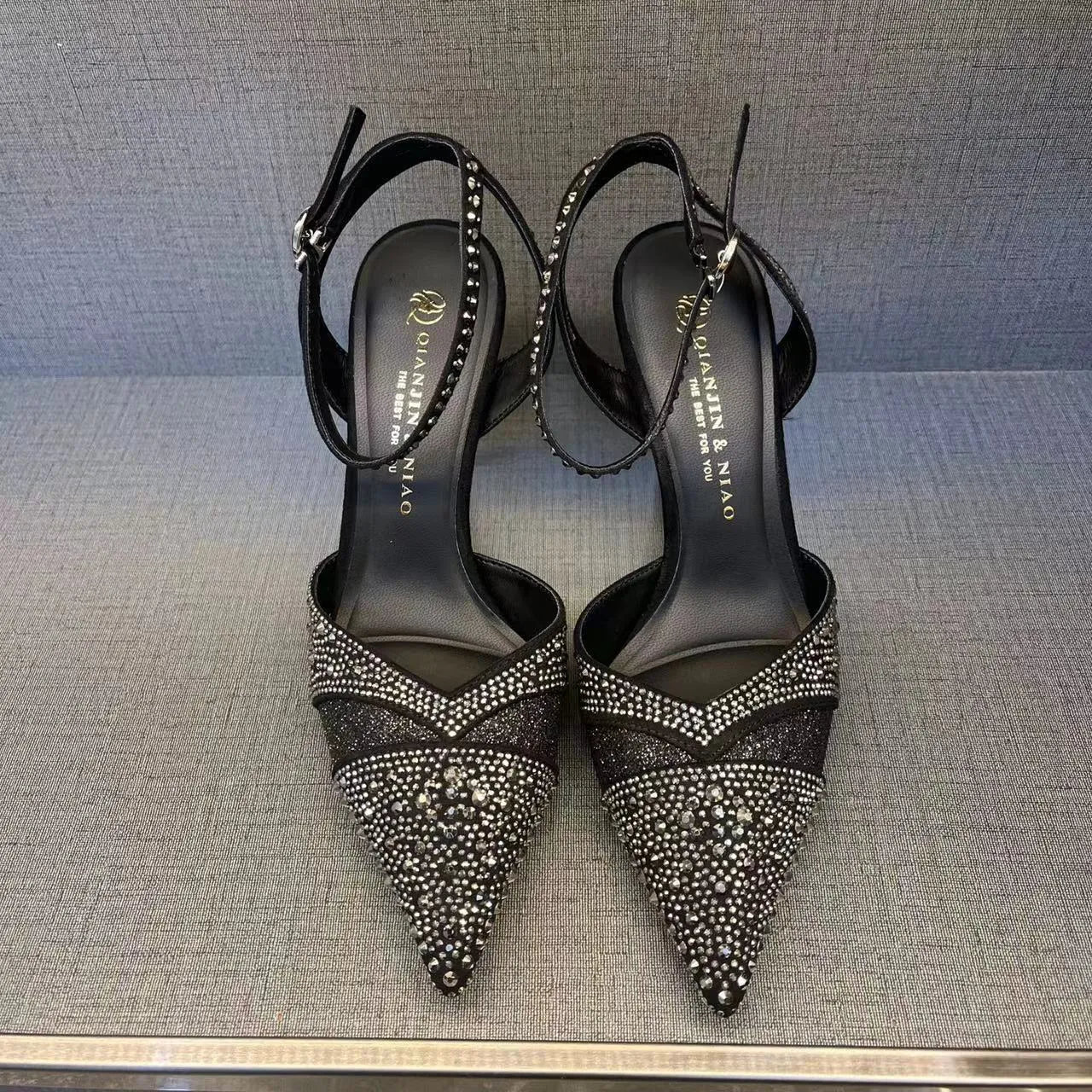 Women's silver and black hollow stiletto high heels with pointed toe and red sole on a plain background.