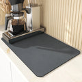 Black square kitchen drain drying mat with anti-slip rubber backing on a countertop