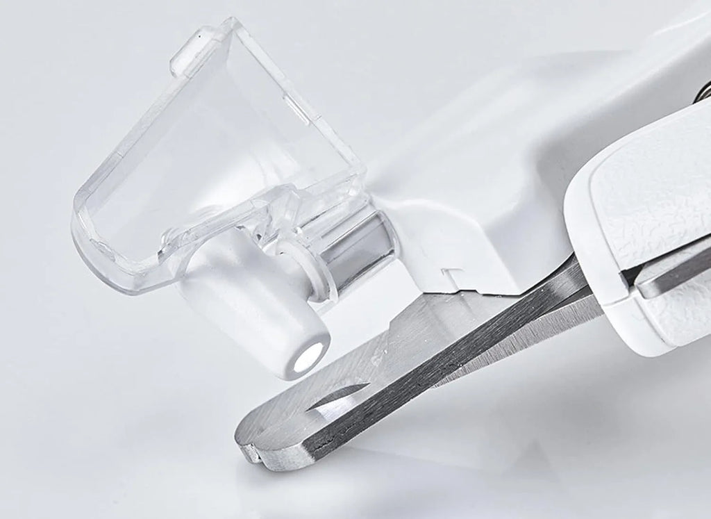 White pet nail clippers with LED light and transparent anti-splash guard next to a nail file on a table