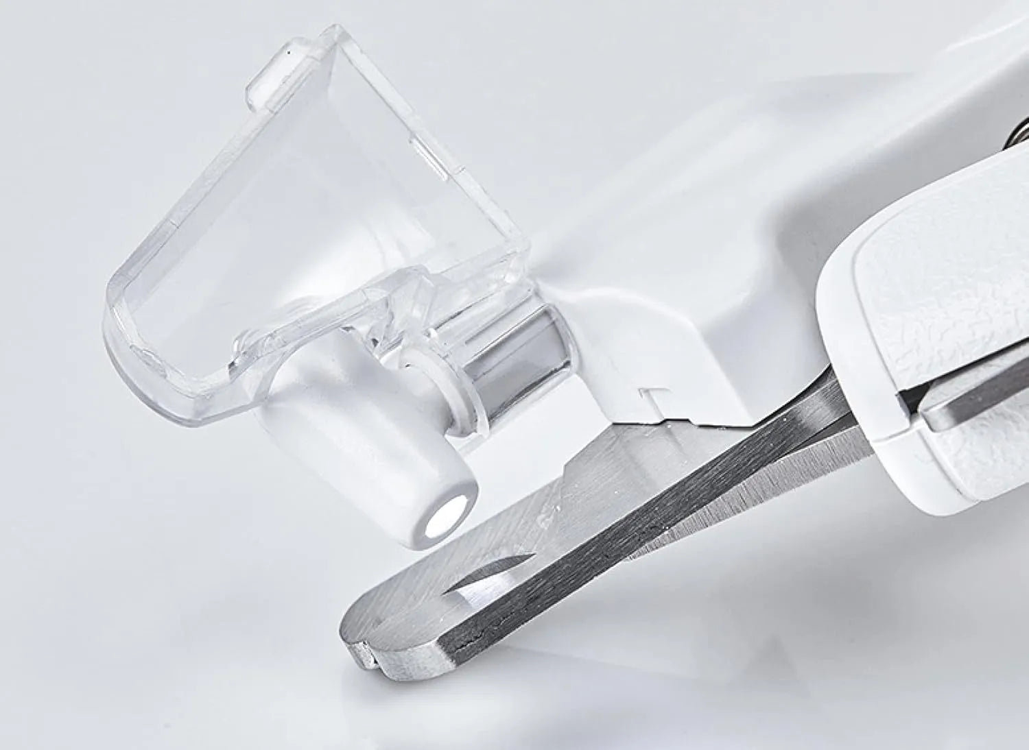 White pet nail clippers with LED light and transparent anti-splash guard next to a nail file on a table
