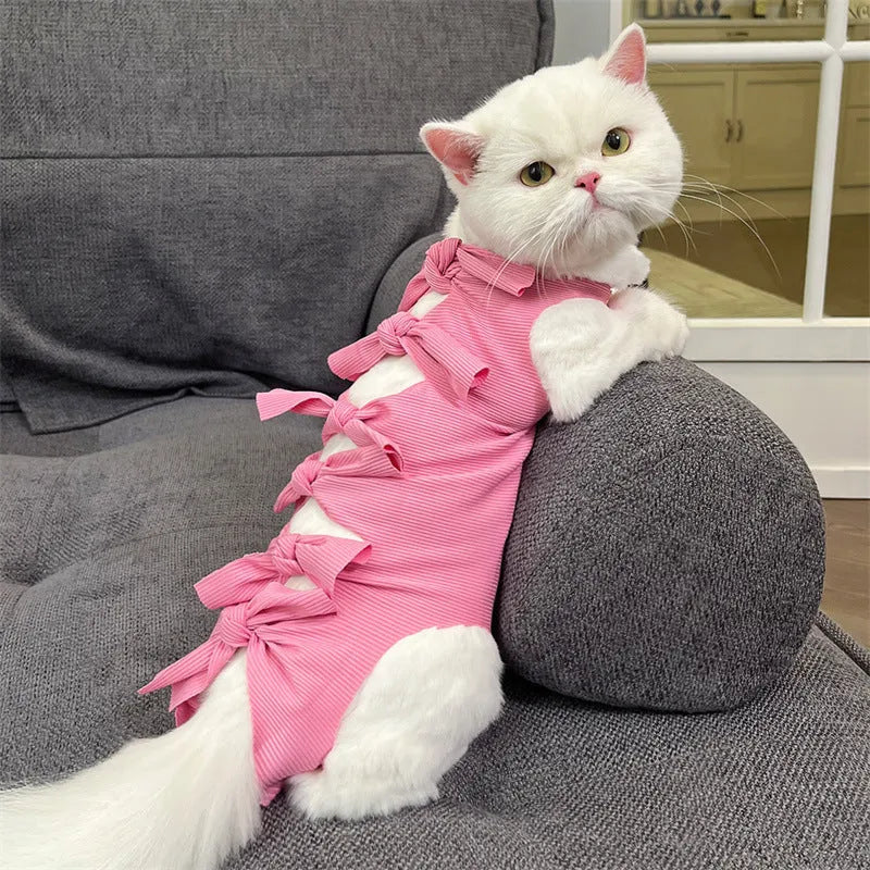 Pink lace-up cat recovery bodysuit on a table, showing back ties and full-body design for post-surgery care.