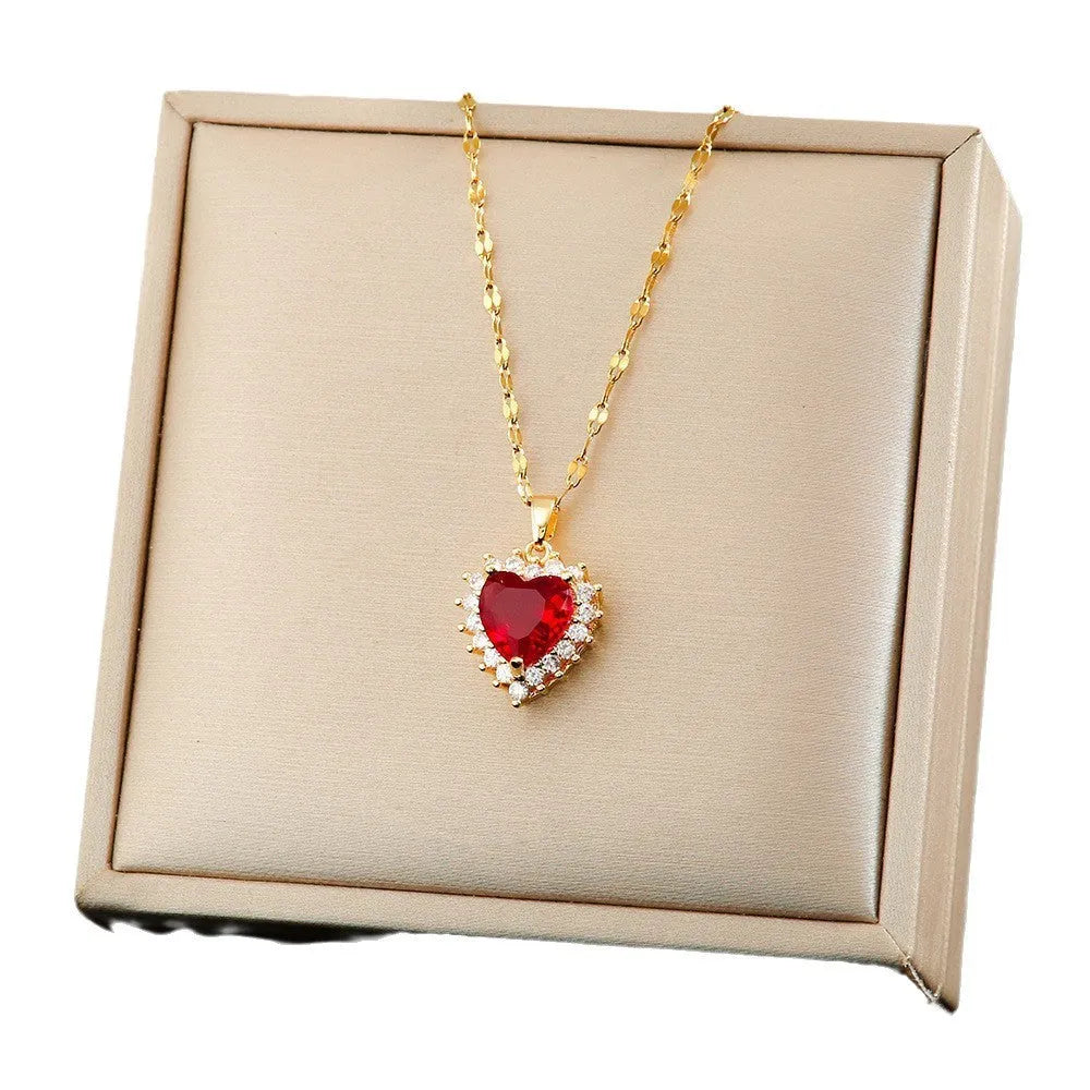 Gold-red titanium steel necklace with heart flower pendant, matching stud earrings, and ring on a grey background.