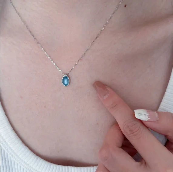 Navy blue water drop pendant necklace on a cross-chain, showing geometric shape and platinum colour accents.