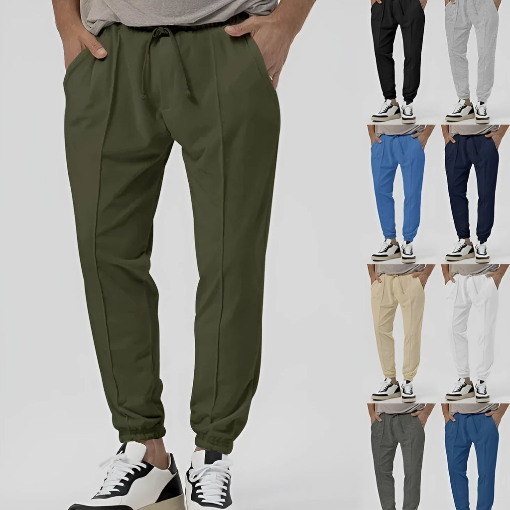 Man wearing grey loose tapered track sweatpants with a micro-elastic cotton blend fabric.
