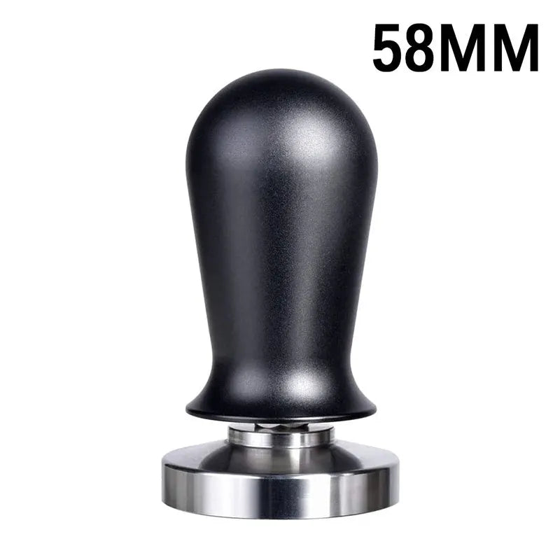 Black and red coffee tamper powder press tool with stainless steel base on a wooden table.
