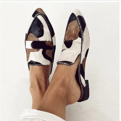 Women's black and white apricot suede pumps with pointed toe, low heel, and animal print.