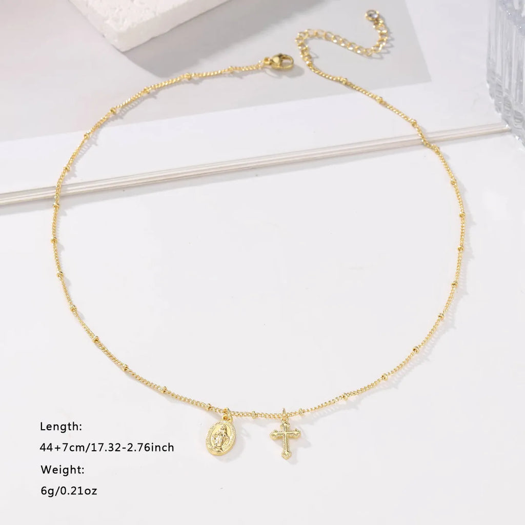 Geometric gold Virgin Mary and cross pendant necklace on a chain, showing minimalist design.