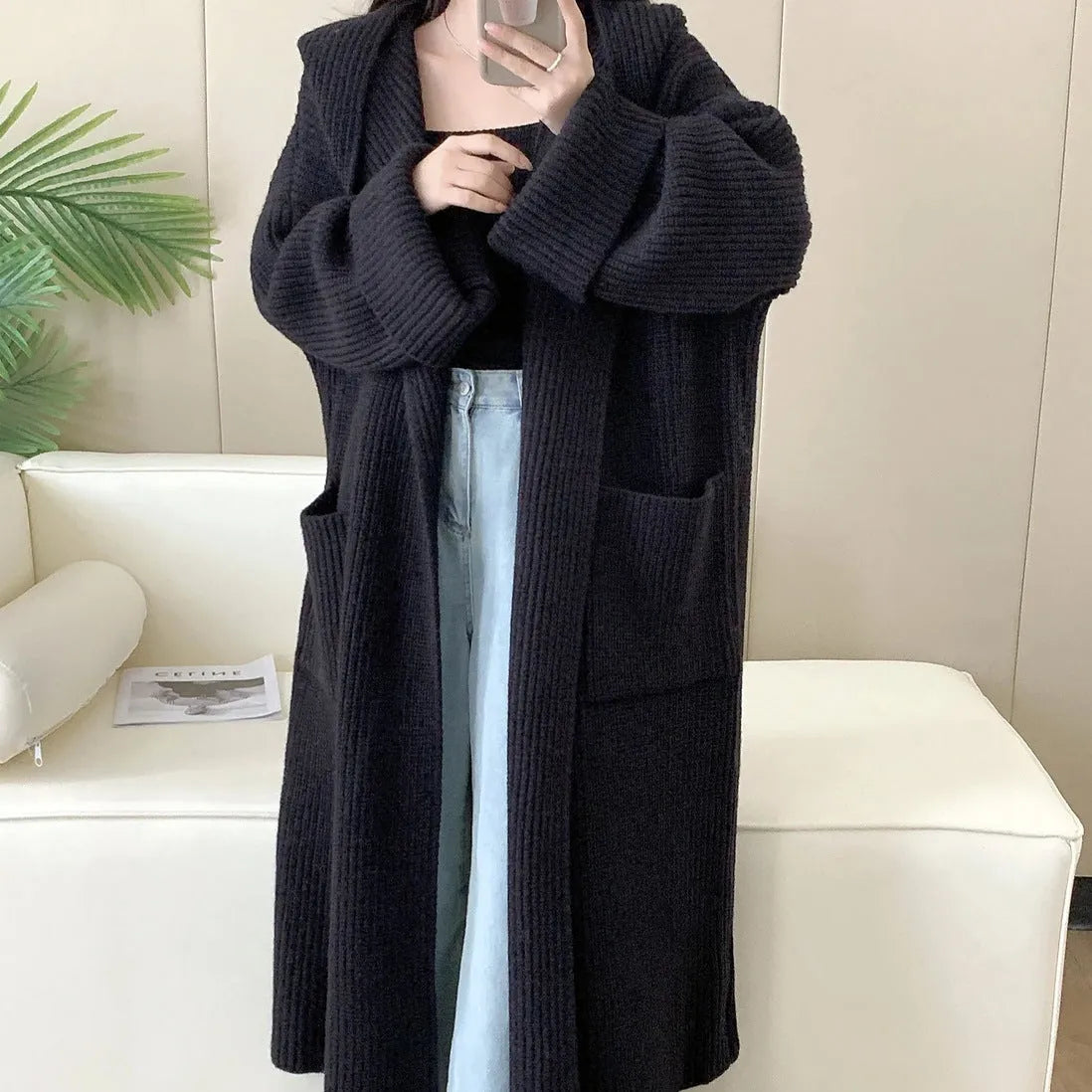 A woman wearing a loose, milky white hooded cardigan coat with raglan sleeves.